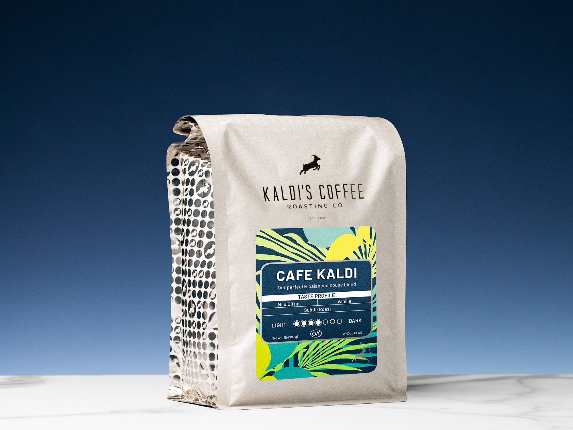 A 2lb bag of Cafe Kaldi sits on marble countertop in front of an uplit blue wall
