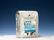 A 2lb bag of Highlander Grogg sits on marble countertop in front of an uplit blue wall