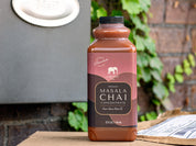 32oz bottle of Organic Masala Chai Concentrate on a doorstep