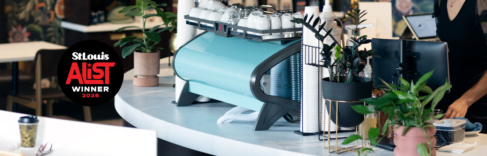 Coffee machine in a cafe setting with 'St. Louis Alist Winner' logo.