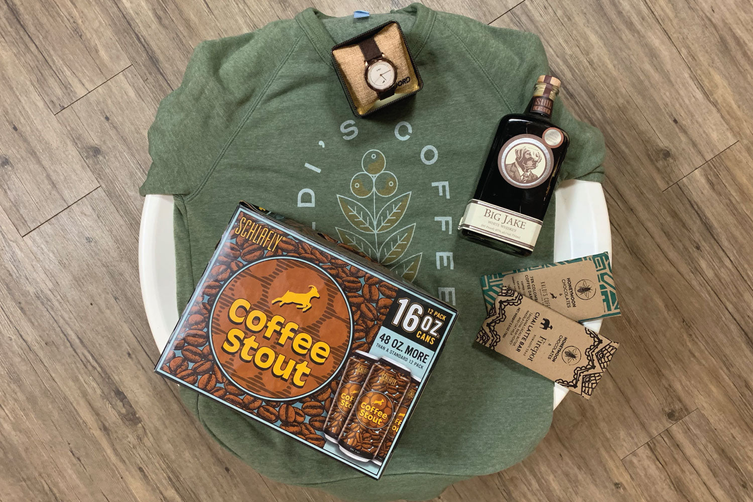 Our green sweatshirt behind a case of Schlafly Coffee Stout, a Jord Barista watch, 2 Honeymoon Chocolate Bars, a battle of Big Jake Breakfast Brew