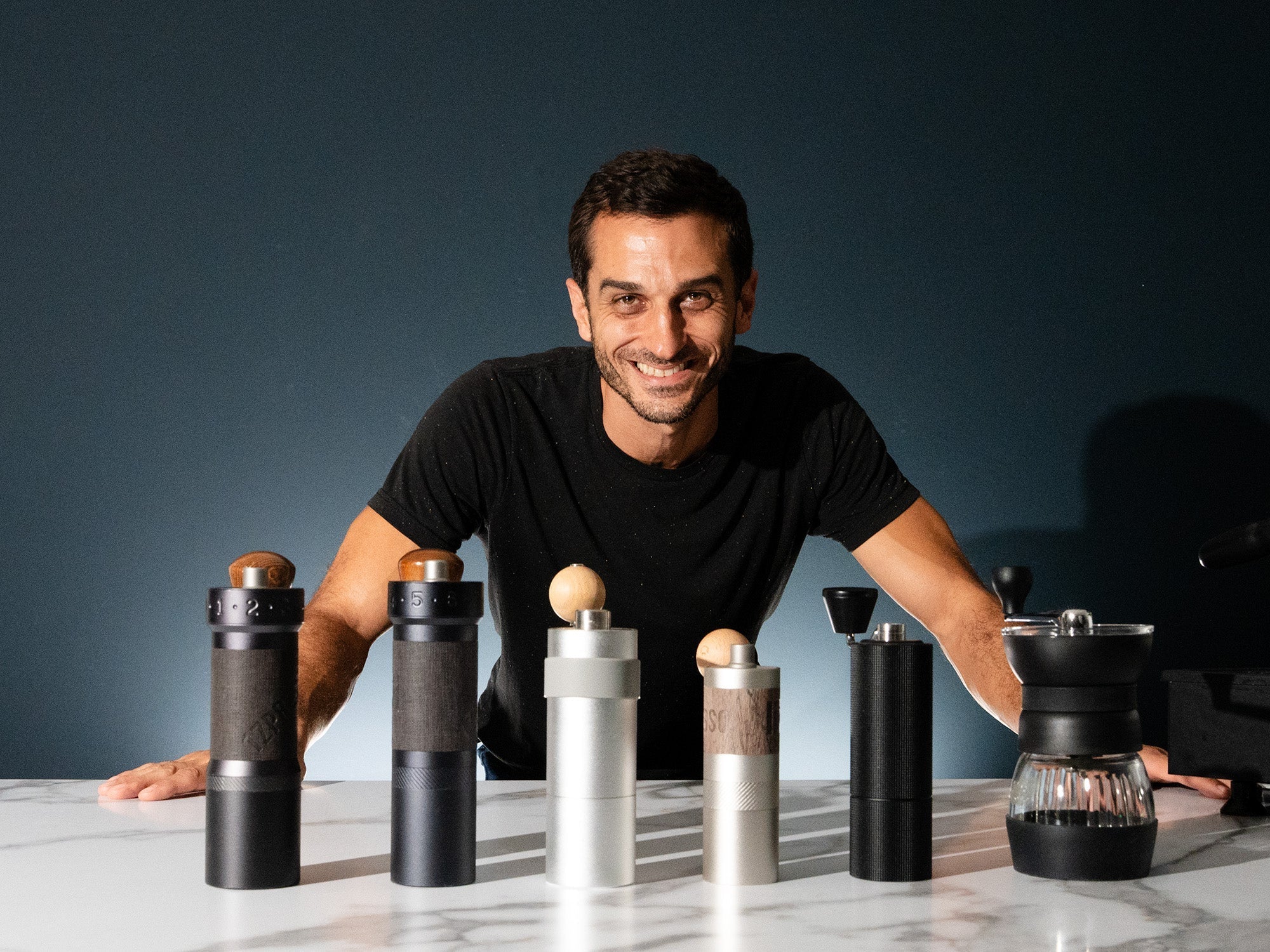 Rob stands with a line up of coffee hand grinders