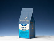 12 oz bag of Dancing Goats Blend on a white marble counter, with a blue background