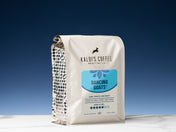 A 2lb bag of Dancing Goats blend sits on a marble countertop, in front of a blue wall