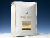 A 5lb bag of Dancing Goats Blend sits on marble countertop in front of an uplit blue wall