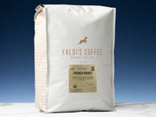 A 5lb bag of Fair Trade Organic French Roast sits on marble countertop in front of an uplit blue wall