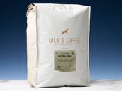 A 5lb bag of Fair Trade Organic Natural High sits on marble countertop in front of an uplit blue wall