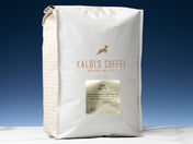 A 5lb bag of Cafe Malta sits on marble countertop in front of an uplit blue wall
