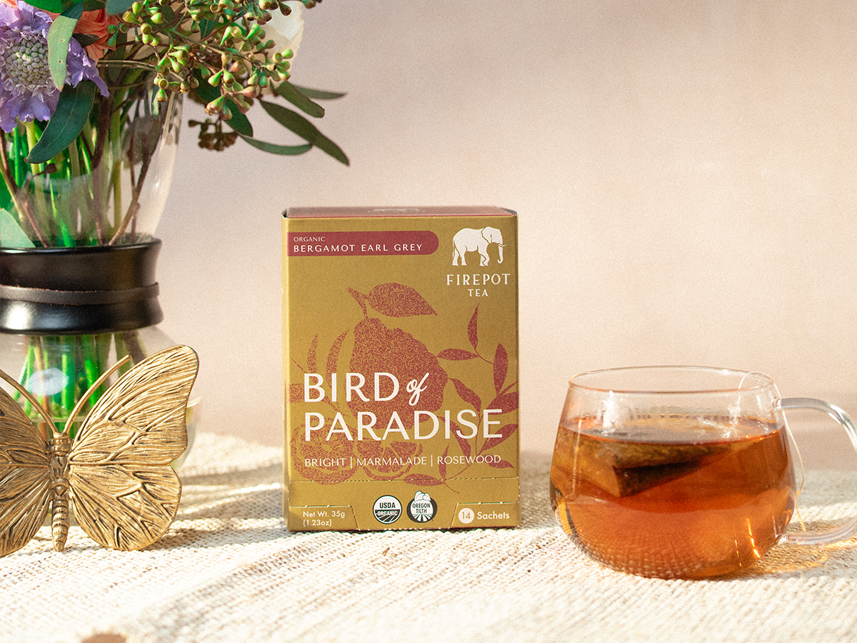 box of bird of paradise sachets and glass mug of black tea