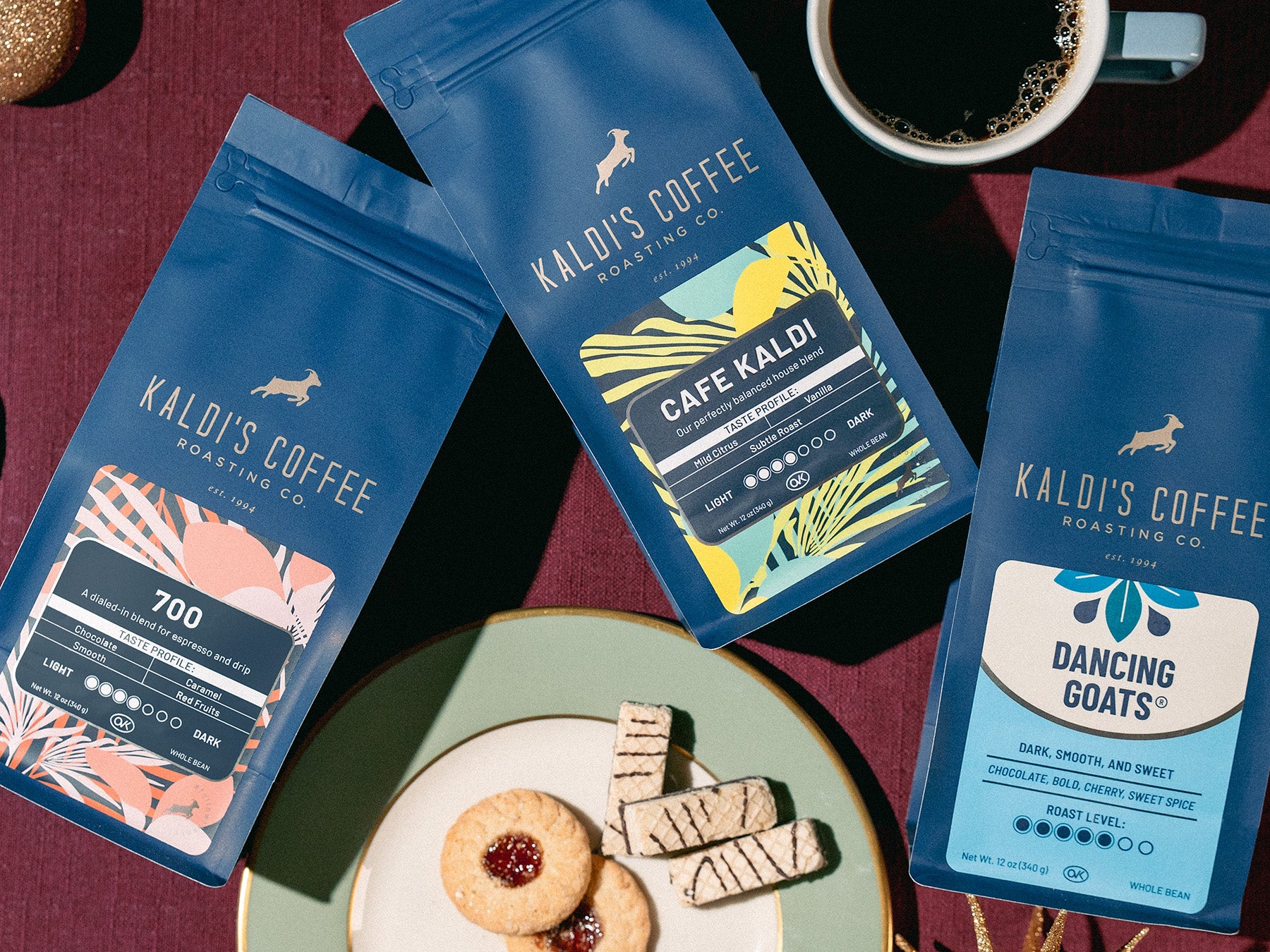 Kaldi's Coffee packages with a cup of coffee and cookies on a red surface