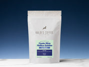 An 8oz pouch of Costa Rican coffee from La Minita sits on a white marble countertop, in front of a gradient blue background that is light blue and ascends into dark blue.