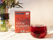 red box of cult of flowers sachets and glass mug of red tea steeping