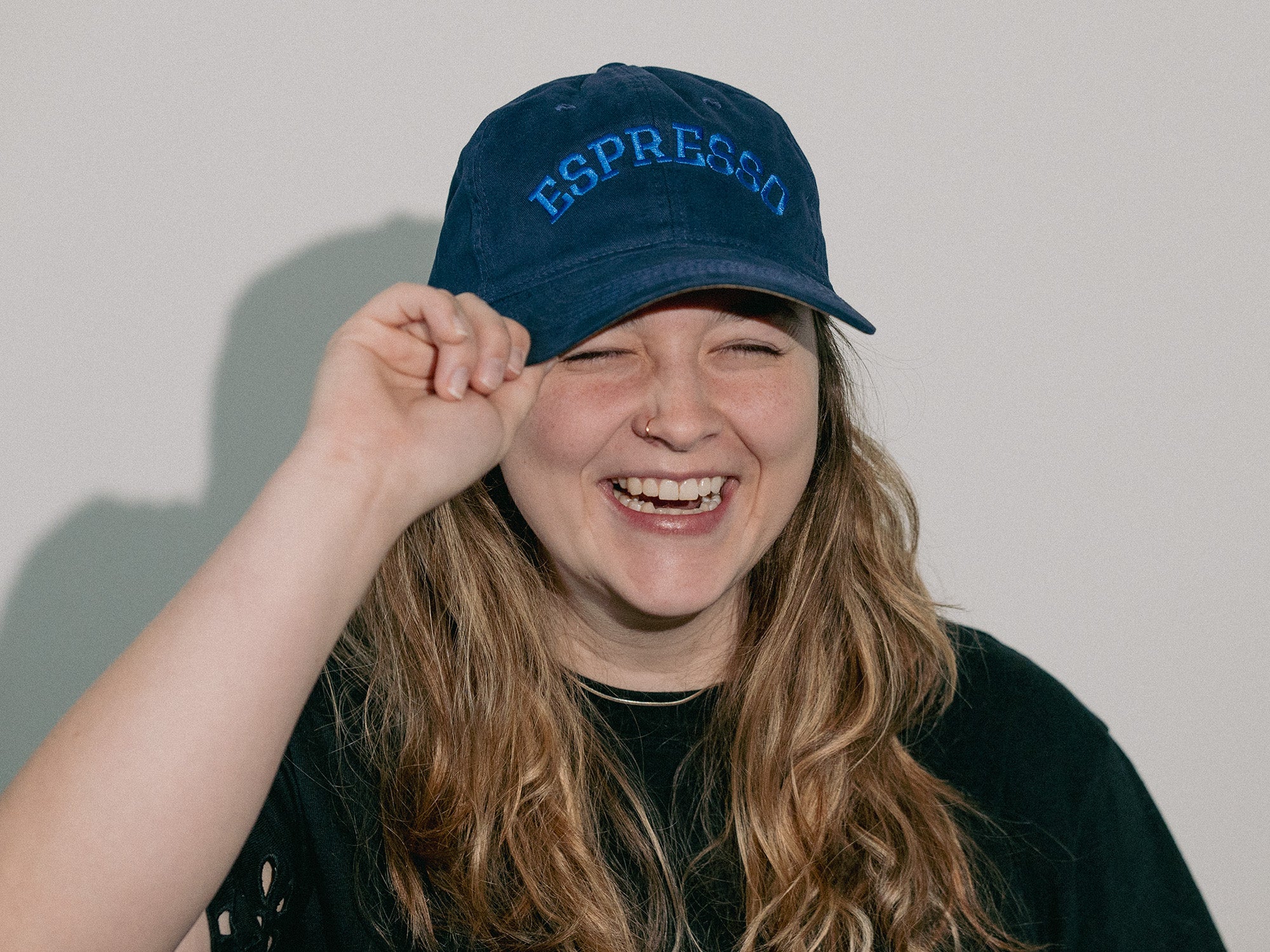 Person wearing a blue cap with 'Espresso' text against a plain background