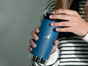 A woman opens the lid of a blue Klean Canteen