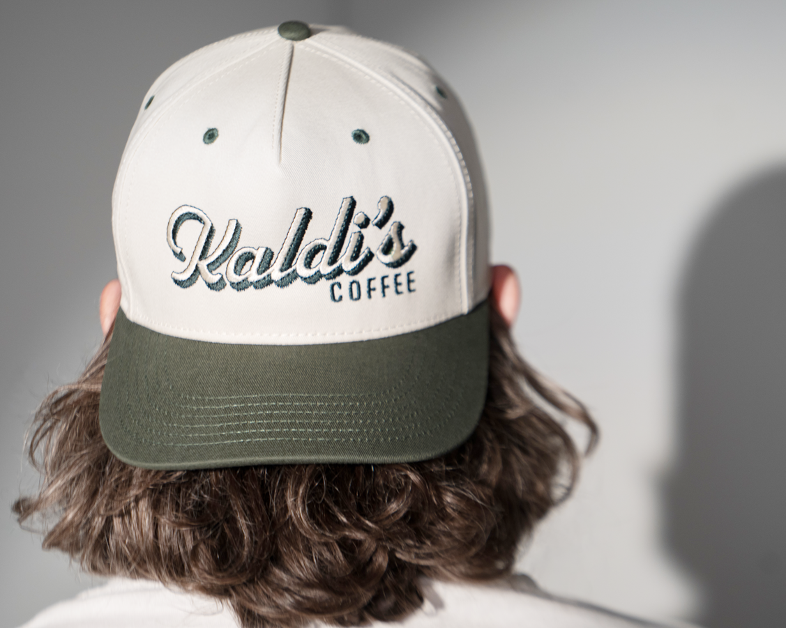 A backwards hat with an dark green brim and a 'Kaldi's Coffee' embroidery.