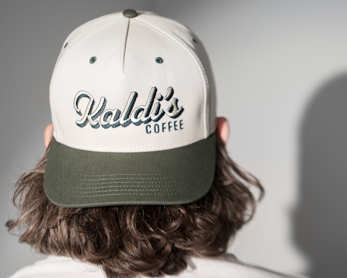A backwards hat with an dark green brim and a 'Kaldi's Coffee' embroidery.