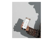 Hand holding a white tumbler with 'Kaldi's Coffee' branding against a light gray background