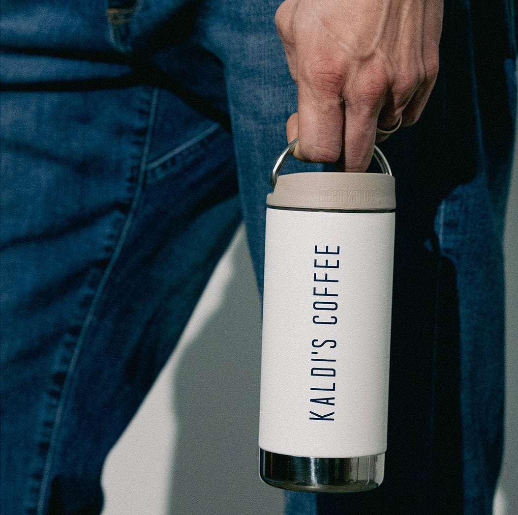 Person holding a white coffee tumbler with 'KALDIS COFFEE' branding.