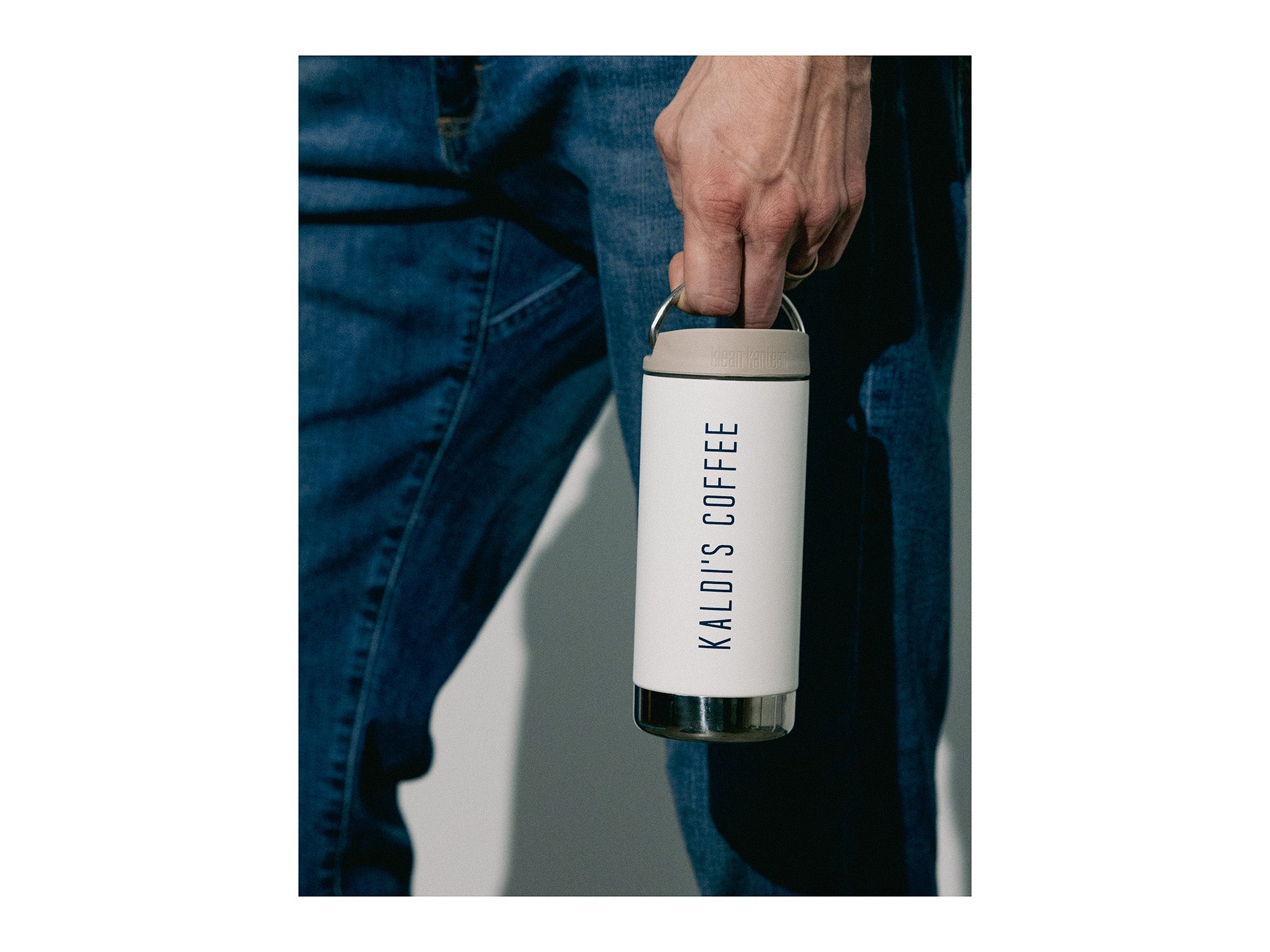 Person holding a white coffee tumbler with 'KALOIS COFFEE' branding.