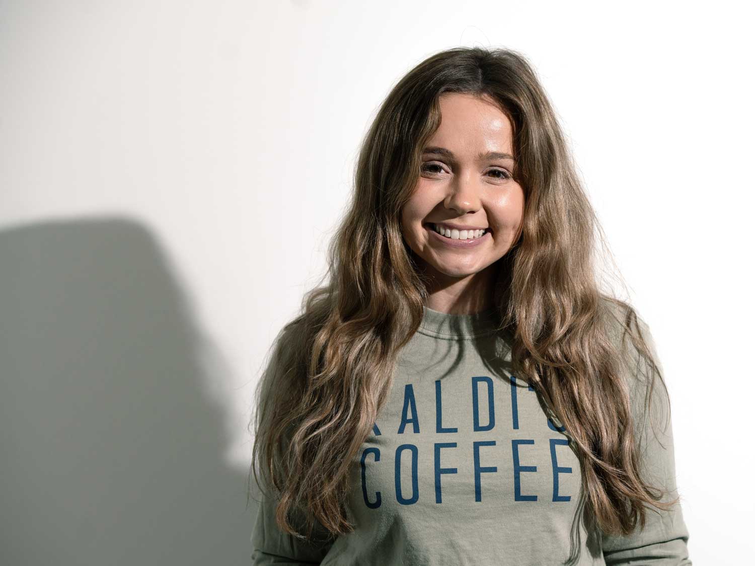 Woman wearing a shirt with 'Baldi's Coffee' text against a plain background