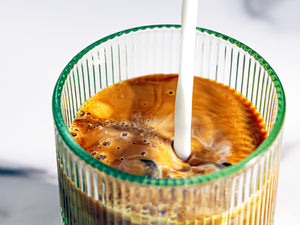 Pouring milk into a glass filled with coffee concentrate