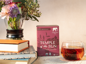 temple of the sun box and glass mug of black tea