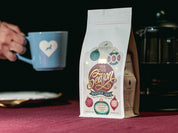 Tis the Season coffee blend with and holding a blue mug