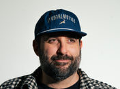 Man wearing a blue cap with text and a logo on a white background