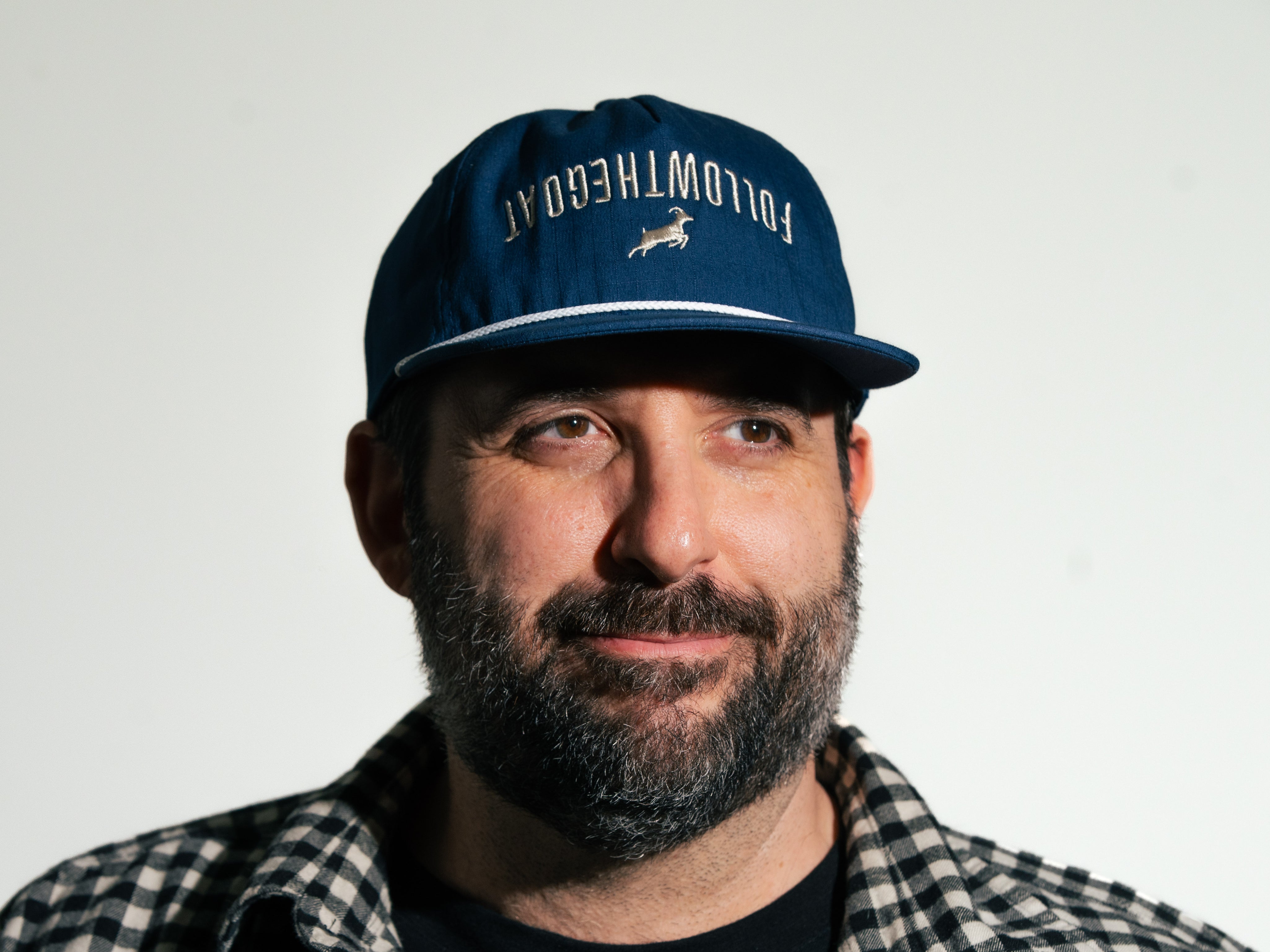 Man wearing a blue cap with text and a logo on a white background