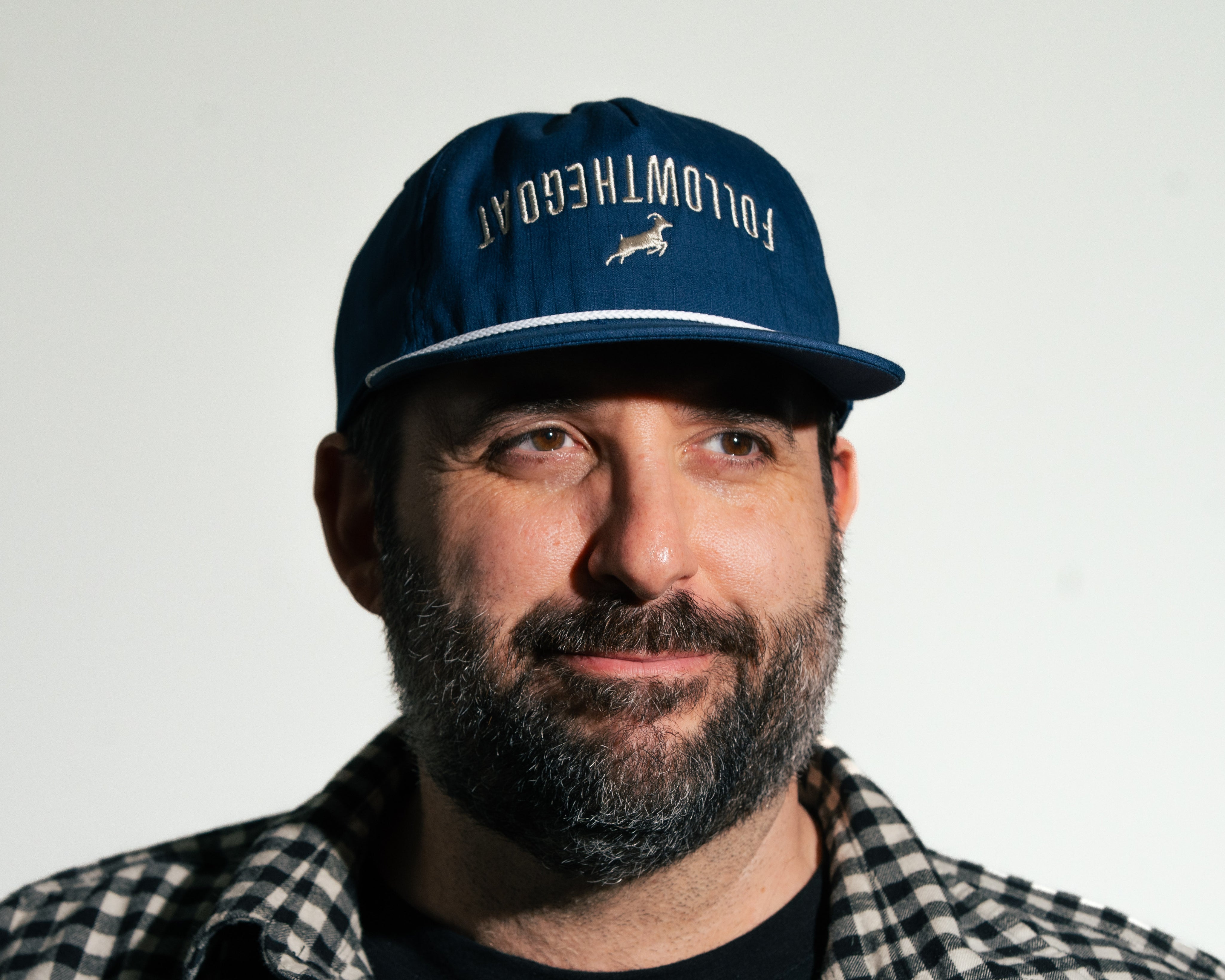 Man wearing a blue cap with text and a logo on a white background