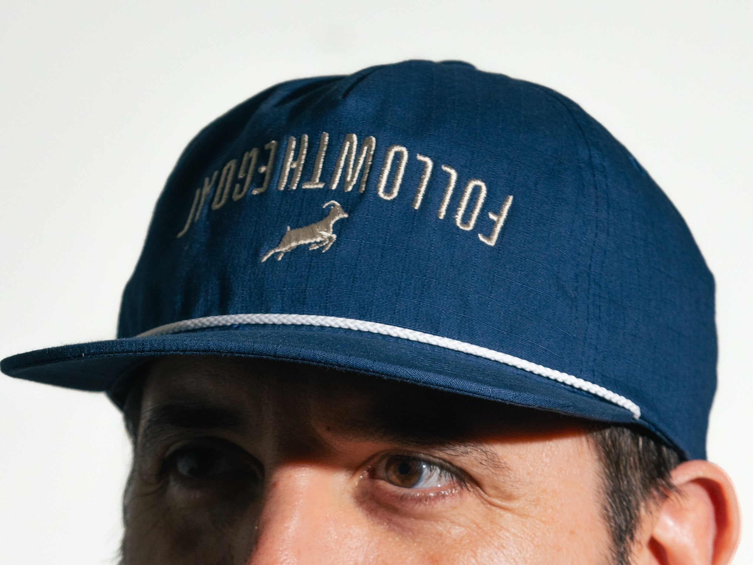 Navy blue cap with 'Follow the Goat' text and a goat logo on a white background