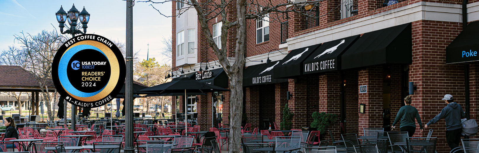 Brick building with outdoor seating area, awnings, and a sign for Best Coffee Shop in 2024.