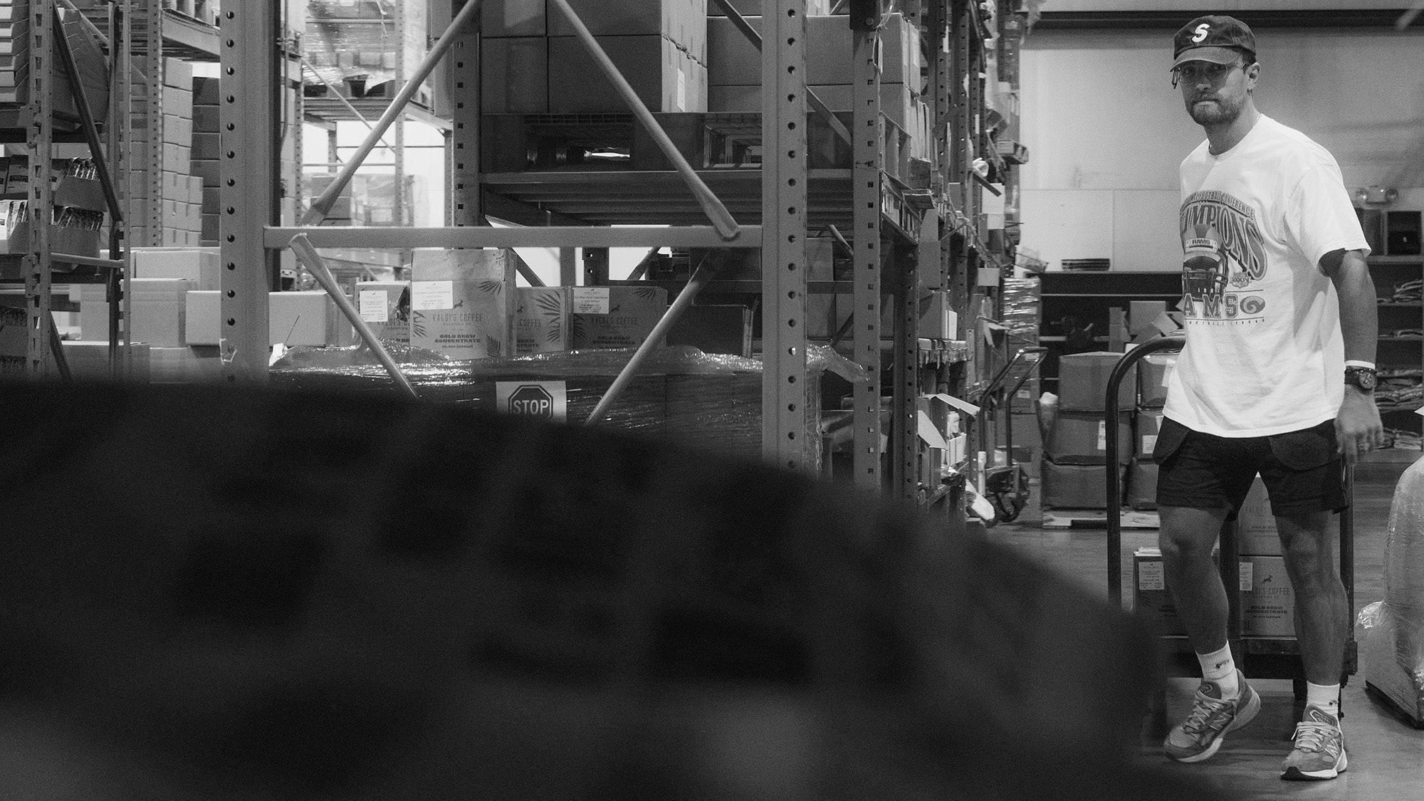 Person standing in a warehouse with shelves and boxes in the background