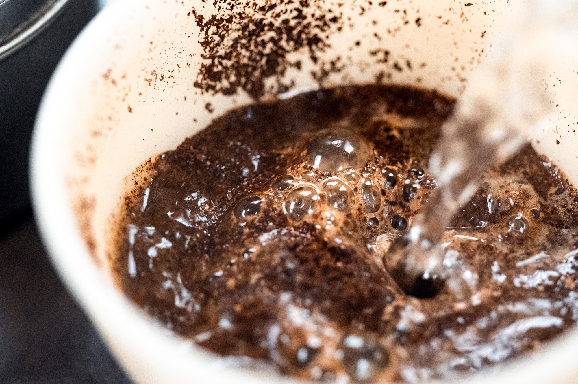 Coffee being poured into a white cupping cup.