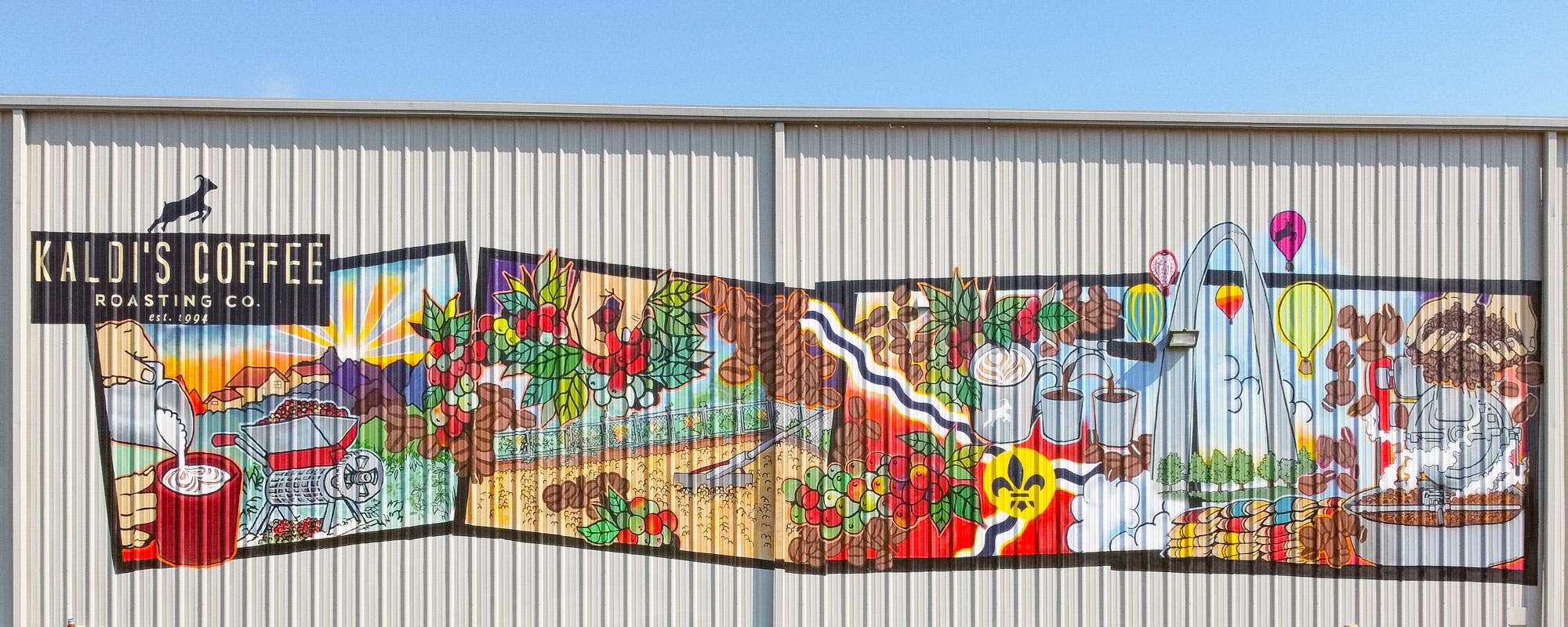 Colorful mural on a building exterior with various scenes and text.