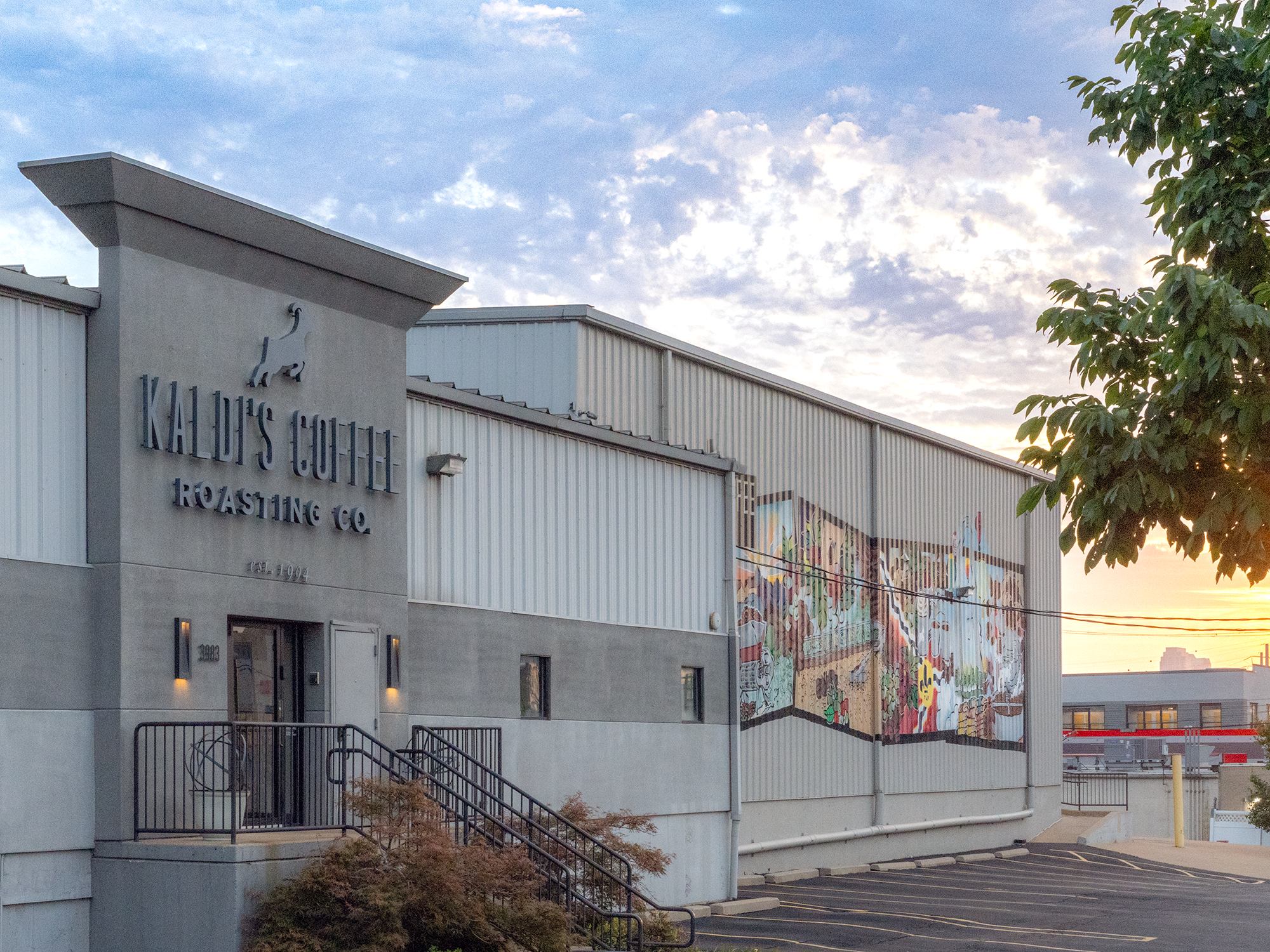 Kaldi's Coffee Roasting Co. building with a mural on the side against a blue sky.