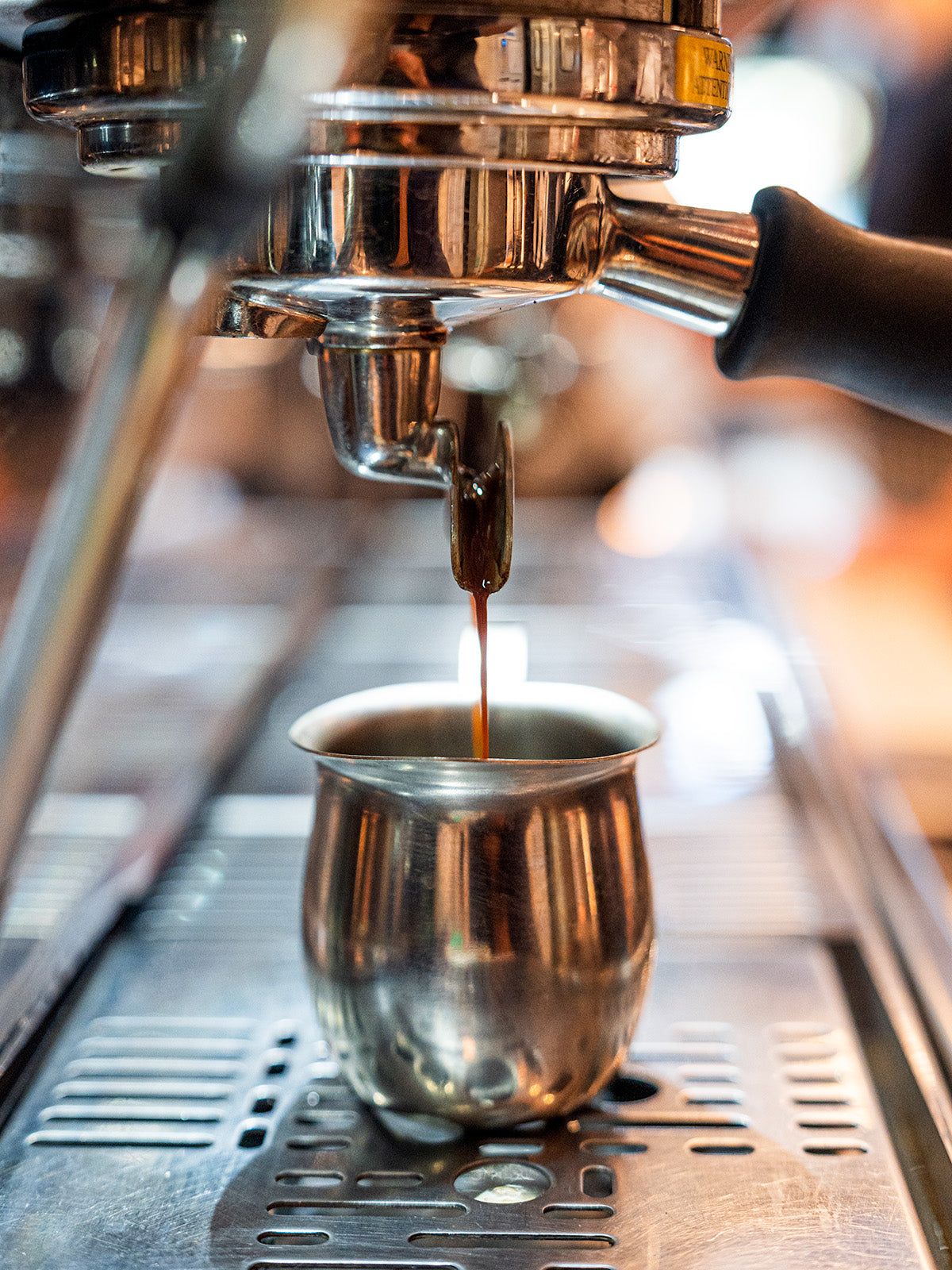 Espresso being brewed into a metal cup from an espresso machine.