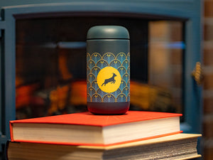 Kaldi's Fellow Carter Move Mug goat on stacked books by fire